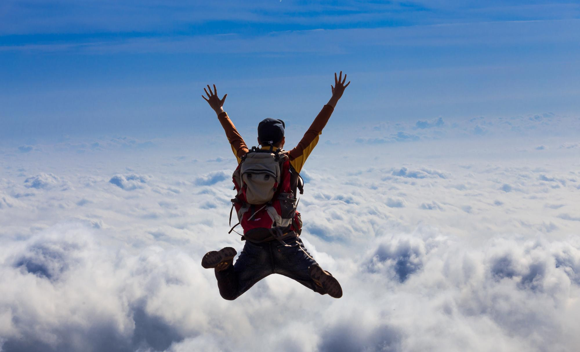 An adventurer jumps into the void above a sea of clouds, capturing the spirit of freedom and adrenaline. Discover extreme sports apparel with Edge Defiers, designed for epic moments.